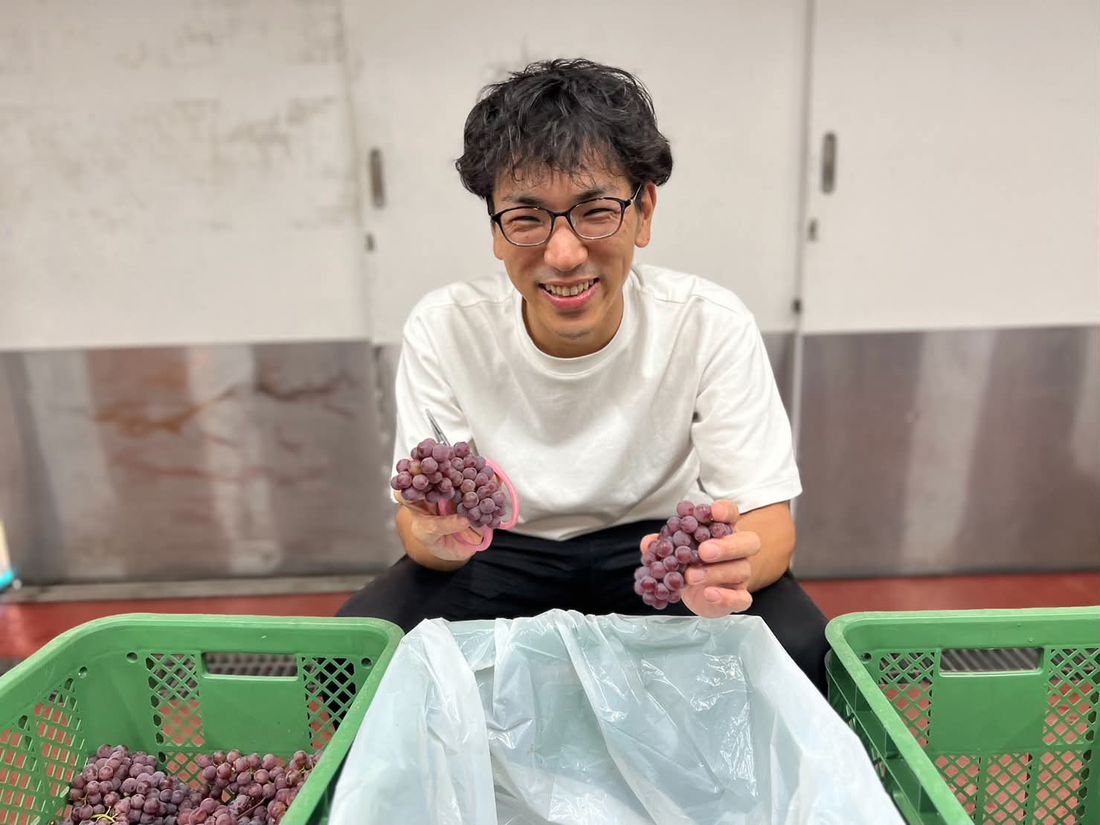 収穫したぶどうを手に笑顔の齊藤 誠也さん